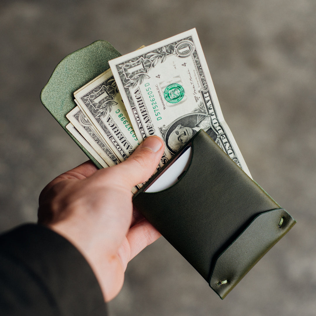 Archer wallet held open by a man's hand, displaying bills and cards inside