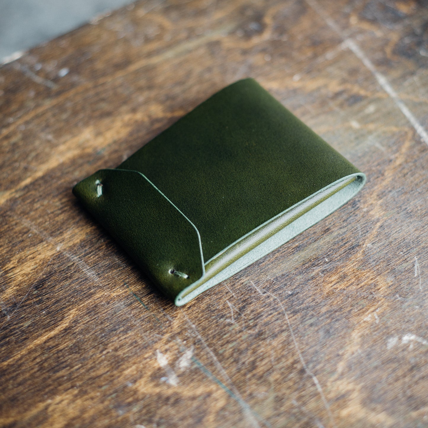 Closed Archer wallet, placed on a brown crafting table, with bills and cards neatly tucked inside