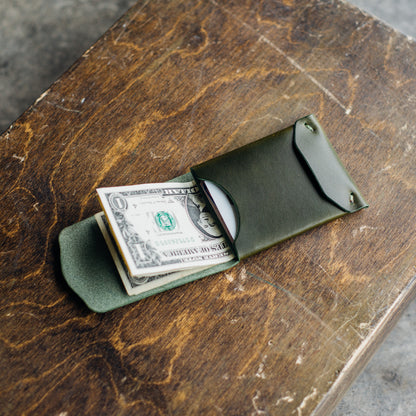 Archer wallet in olive color with bills and cards inside, placed on a brown crafting table.