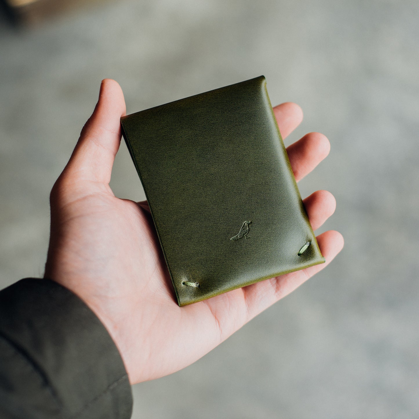 Closed Archer wallet held by a man's hand, with bills and cards neatly tucked inside