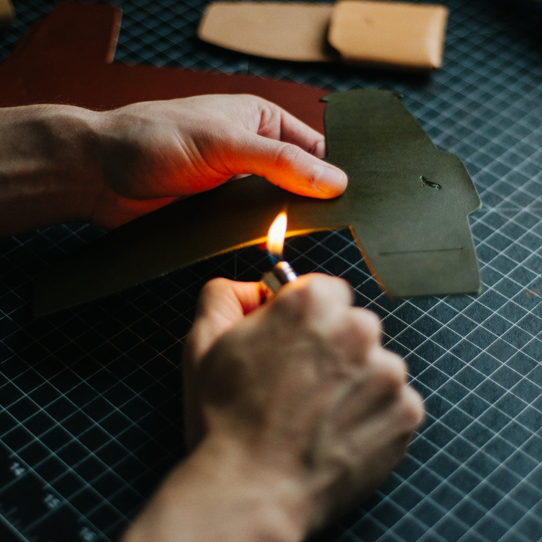 Crafting a Olive Cash Emerson Wallet: A man is seen working on the wallet against a backdrop featuring other color variations of the product and various crafting tools