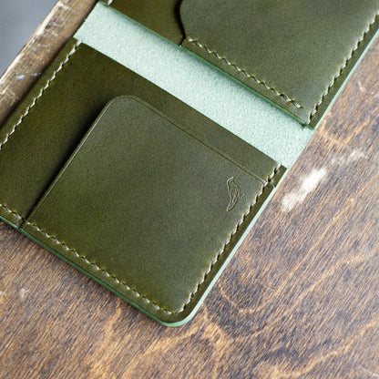 Olive opened Pattern - Garrison Wallet displayed on a brown table viewed from close.