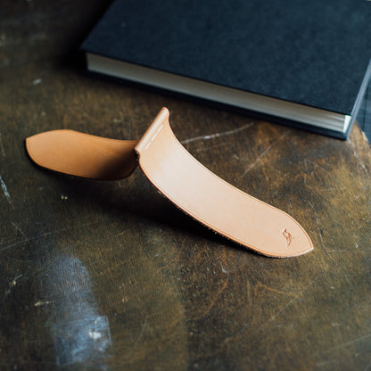 Sophisticated hand-stitched leather bookmark crafted from premium Buttero leather. Laid open on a crafting table with a book in close proximity