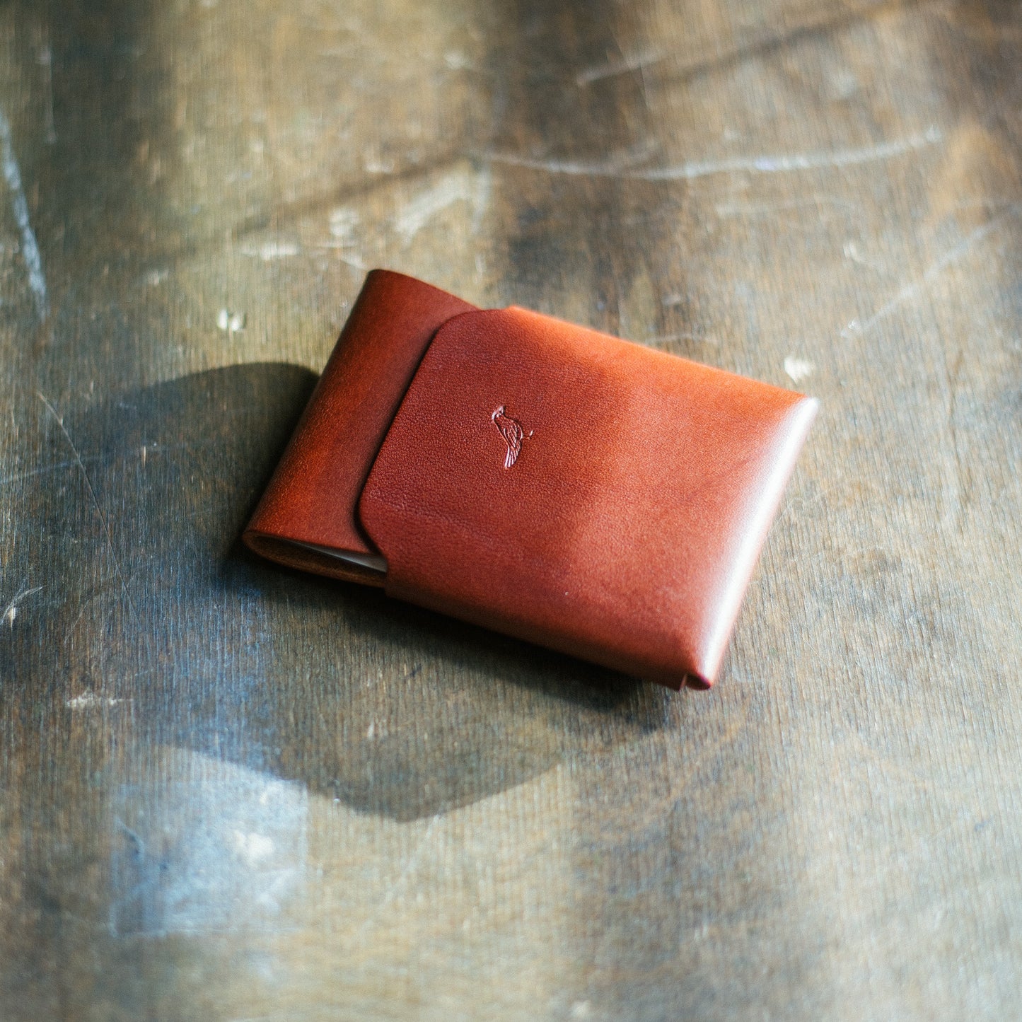 Brown Pattern Emerson Wallet with bills and cards neatly tucked inside on a worktable 