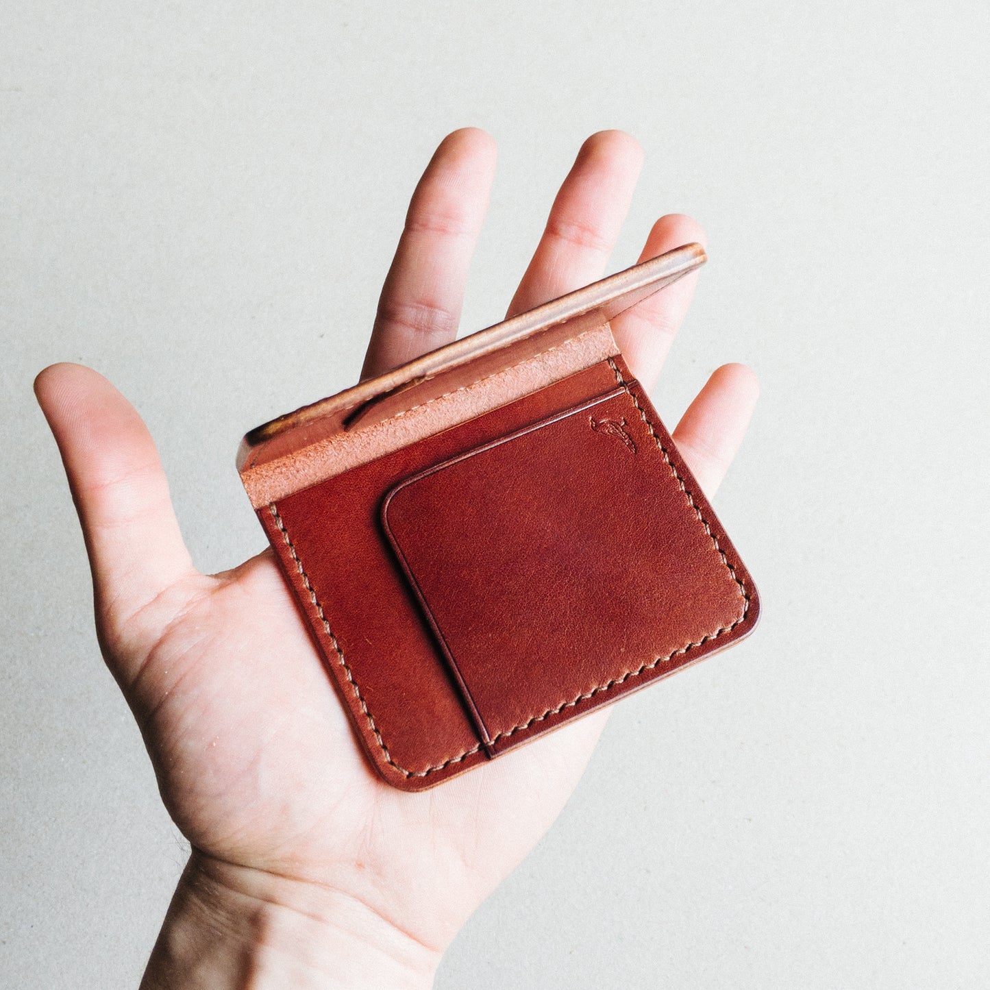 Opened Brown Pattern - Garrison Wallet held by a man against a white blurred background.