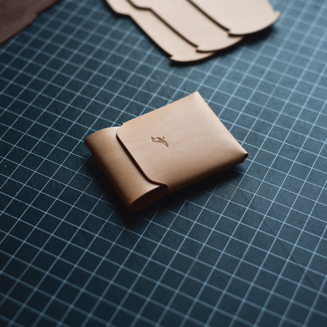 Natural Cash Emerson Wallet with bills and cards neatly tucked inside on a workbench viewed from the side