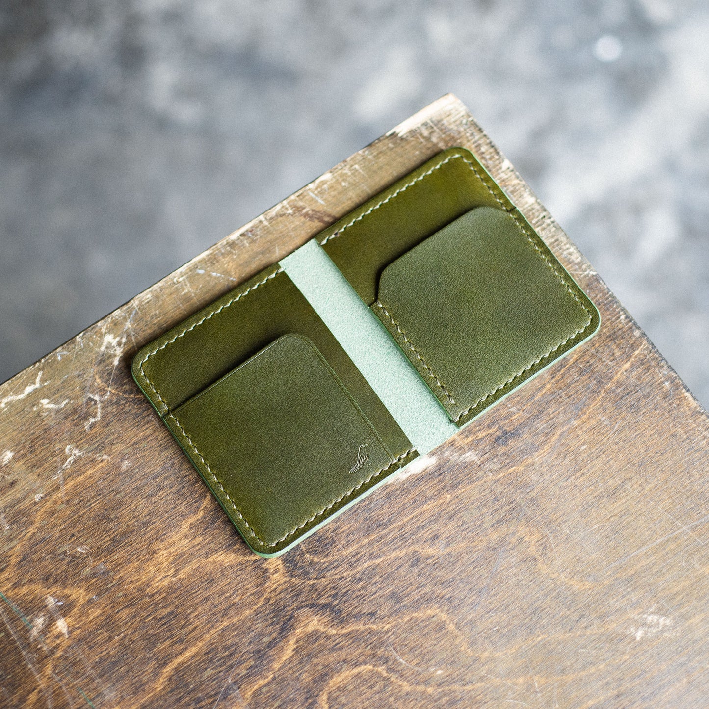 Olive opened Pattern - Garrison Wallet displayed on a brown table.